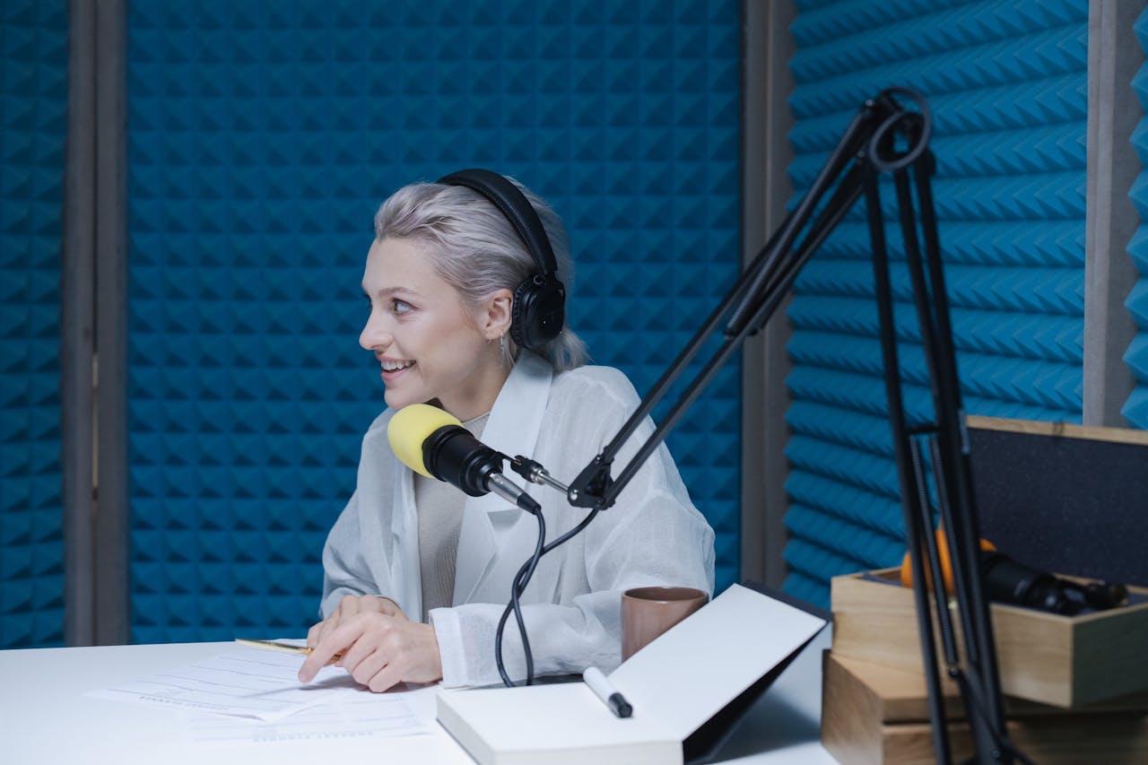 about-02 Woman wearing headphones recording a podcast in a soundproof studio with a microphone.